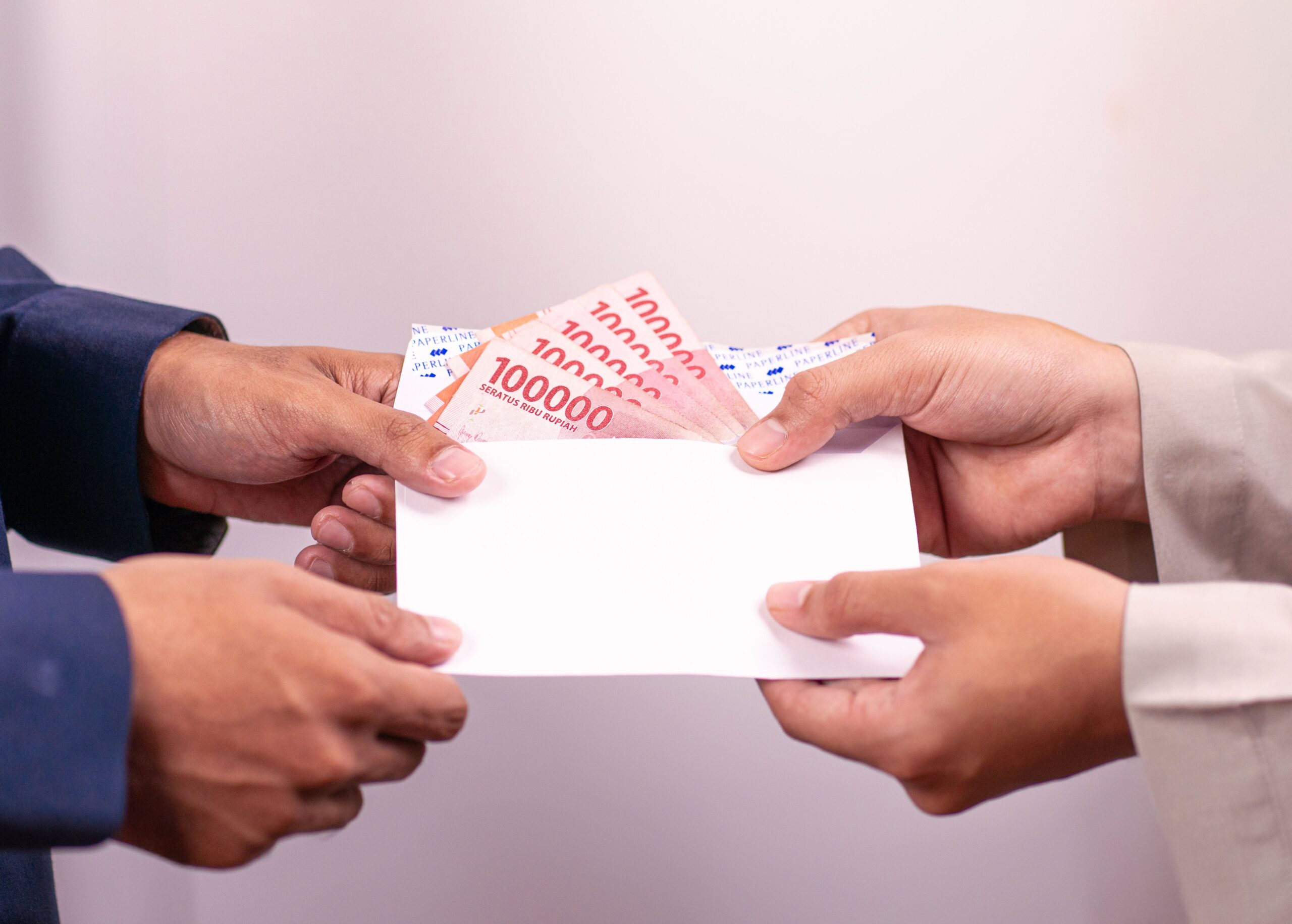 Ilustrasi amplop berisi uang Rupiah yang berpindah tangan sebagai simbol gratifikasi dalam hukum tipikor